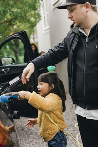 Girl helping father in charging car while going for picnic