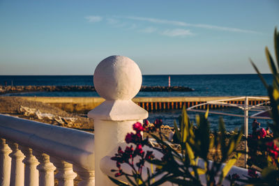 Close-up of railing by sea against sky