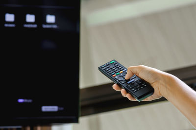 Female hand with tv remote control in the room