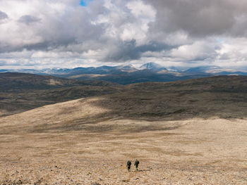 People walking on landscape against sky