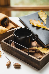 Cozy fall morning at home. coffee cup, book and autumn leaves on wooden tray.