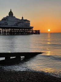 Pier over sea against sky during sunset