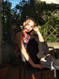 Portrait of young woman sitting on chair at patio