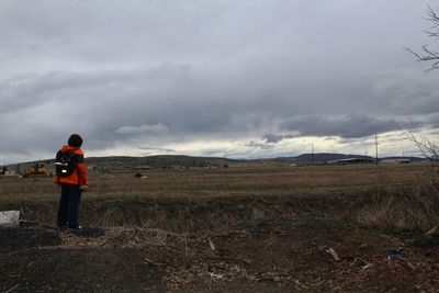 View of field against cloudy sky