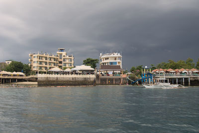 Buildings by river against sky in city