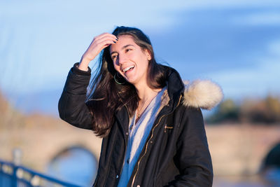 Portrait of young woman standing against sky