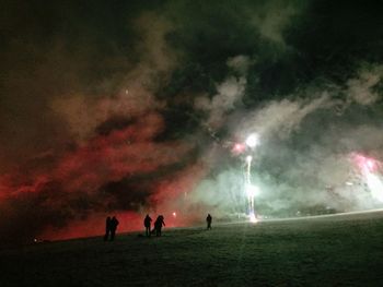 Silhouette people on field against sky at night