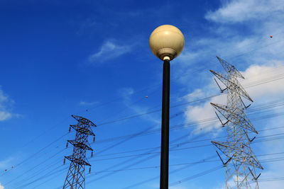 Low angle view of electricity pylon against blue sky