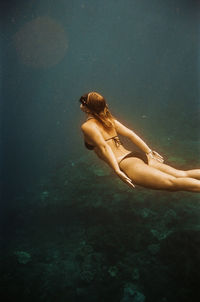 Woman free diving near nusa penida, bali, indonesia. nikonos v on 35mm cinestill 400d film.