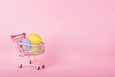 Close-up of shopping cart with eggs against pink background