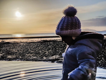 Man looking at sea against sky during sunset