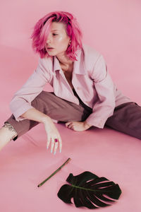 Young woman sitting over colored background