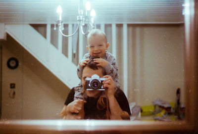 Portrait of girl holding camera at home