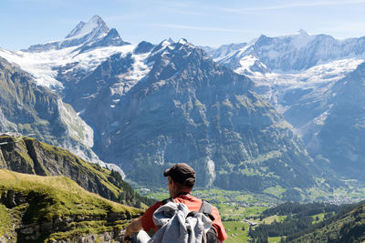 Rear view of hiker sitting against mountain