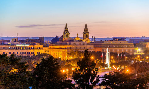 Illuminated buildings against sky at dusk