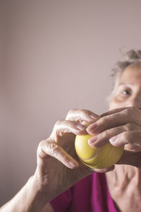 Close-up of woman holding stress ball while sitting against brown background