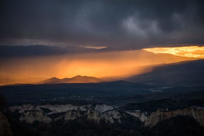 Scenic view of mountains against dramatic sky at sunset