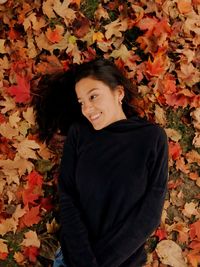 Smiling woman lying on autumn leaves