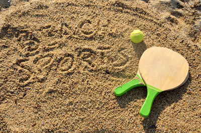 Pair of rackets and ball for sport on the beach with an inscription on the sand 'beach sports'