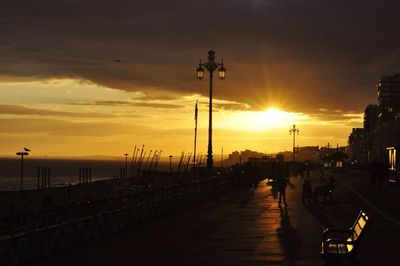 People at street light against sky during sunset