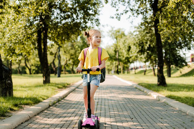 A beautiful little girl rides a scooter on her way back to school