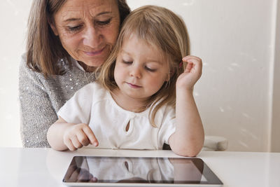 Grandmother with granddaughter using digital tablet