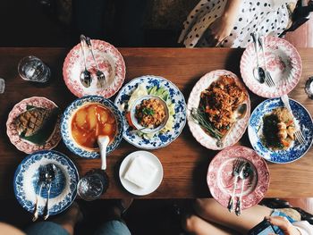 Directly above shot of food on table by people at restaurant