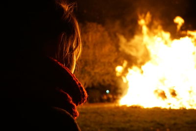 Close-up of woman looking away by fire at night