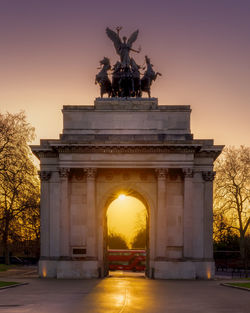 Statue in city at sunset