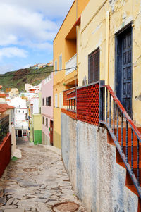 Empty walkway amidst buildings against sky