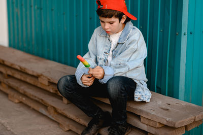 Boy in a red cap  crying against the background of a blue wall. he holds colorful ice cream