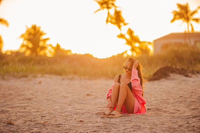Full length of woman standing on sand at beach during sunset