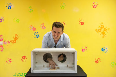 Portrait of young man using mobile phone against wall