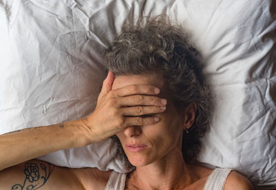 Directly above shot of woman with head in hand sleeping on bed at home