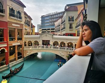 Woman on bridge over river in city