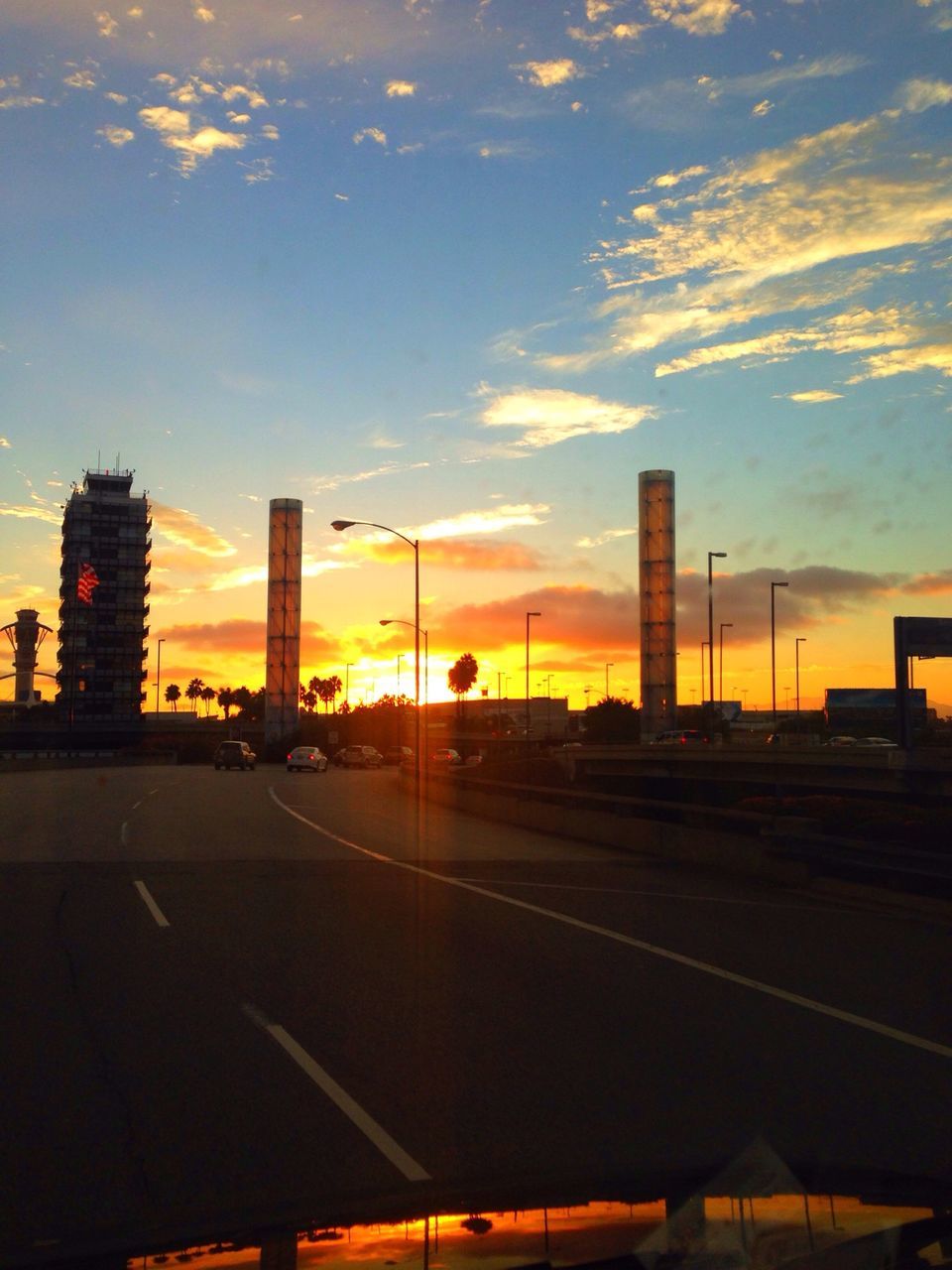 sunset, building exterior, architecture, sky, built structure, city, transportation, road, cloud - sky, orange color, silhouette, street, road marking, cloud, car, building, street light, outdoors, no people, office building