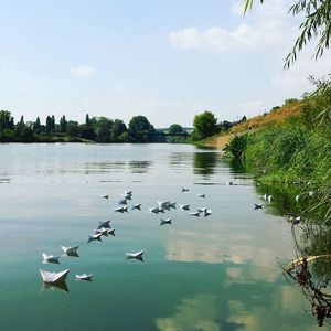 Paper boats in lake against sky