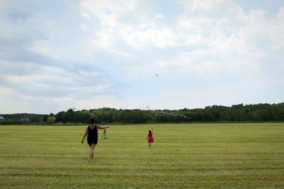 Rear view of mother with daughter playing on grassy field at park