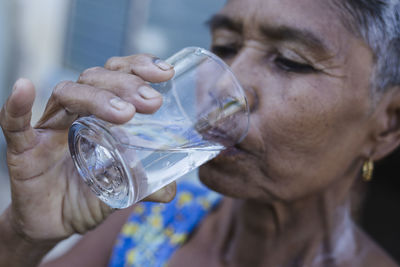 Close-up of man drinking glass with water