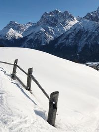 Snow covered field by mountain against sky