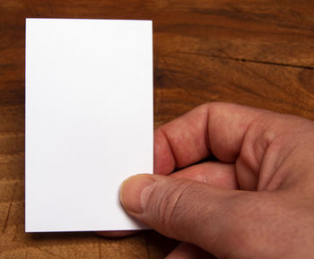 Close-up of person holding paper with text on table