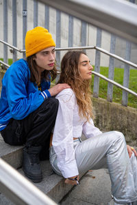 Portrait of smiling young woman sitting on railing