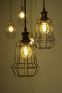 Close-up of illuminated light bulb hanging on wall