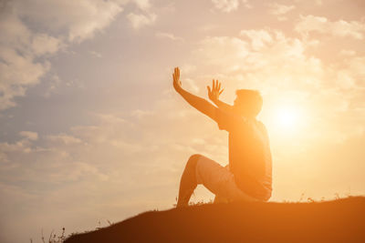 Low angle view of silhouette man sitting against sky during sunset