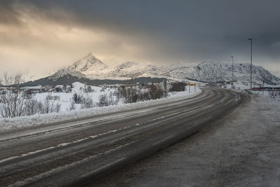 Road by snowcapped mountain against sky