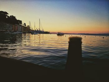 Boats moored in sea at sunset