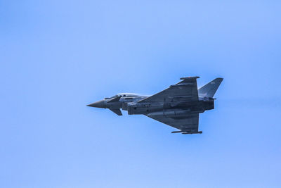 Low angle view of airplane flying against clear blue sky