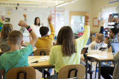 Children raising hands in classroom