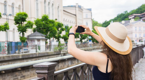 Rear view of woman wearing hat against buildings in city