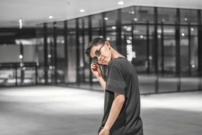Side view of young woman standing against building in city